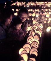 Family gazes at bamboo lanterns lit to mourn war dead